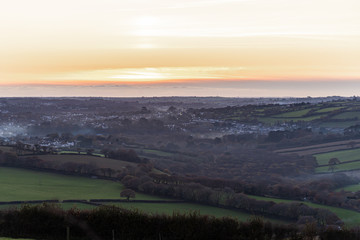 Wood smoke haze at sunset over the landscape of Cornwall in autumn