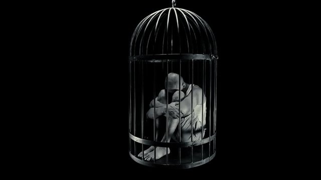 a man in a bird&rsquo;s cage is held captive, bowed his head in despair, maybe each of us is locked in his own cage 4K