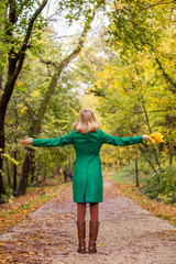 Woman with her arms outstretched holding fall leafs and enjoys in autumn.