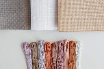 flatlay creativity: canva aida beige, gray and white and multi-colored floss thread, all for cross stitching 1