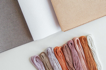 flatlay creativity: canva aida beige, gray and white and multi-colored floss thread, all for cross...