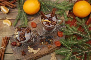 mulled wine hot drink or tea with spices and spices on a wooden background with a branch of spruce. Traditional winter drink. Christmas concept, background, banner, menu. Top view. Flat lay.