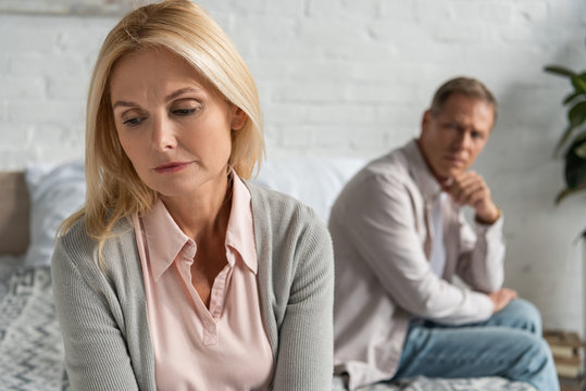Selective focus of worried woman with husband sitting on bed