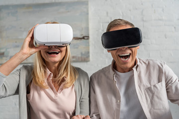 Laughing couple in virtual reality headsets at home