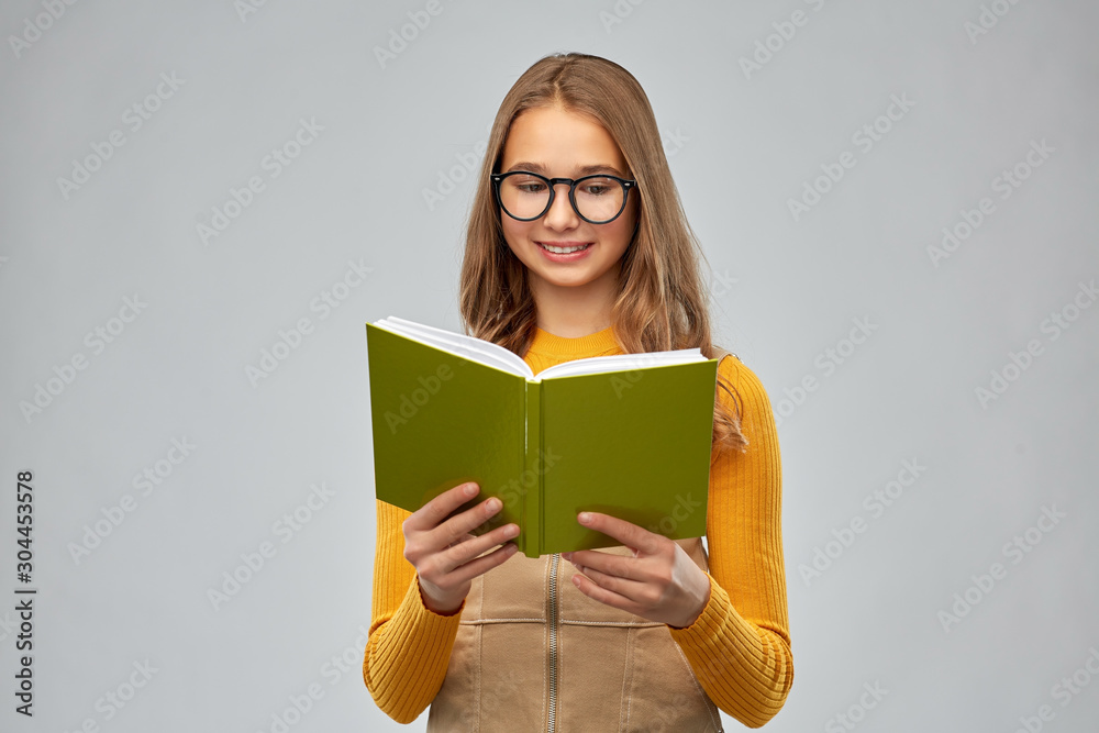 Poster high school, education and vision concept - smiling teenage student girl in glasses reading book ove