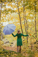 Woman holding umbrella and fall leafs while standing in the park.	