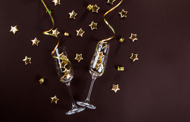 Champagne glasses and star confetti on a dark background top view
