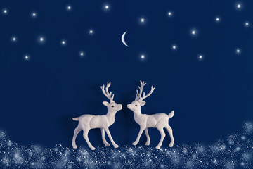 White Christmas reindeer on blue background with snow, stars and moon. Xmas greeting card with wishes. Flat lay.