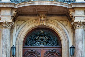 Antique entrance door with decorative elements and wrought iron and street lamps