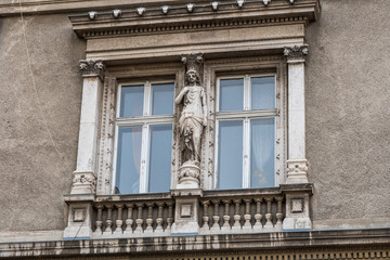 Obraz premium Vintage window with decorative elements and sculptures in old european historical building
