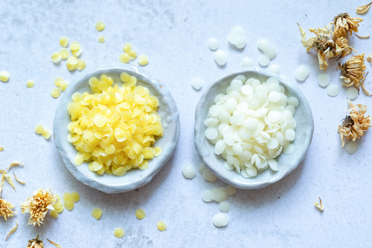 yellow and white cosmetic beeswax pellets in white ceramic bowl for homemade natural beauty and D.I.Y. project.