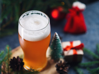 A glass of Christmas beer on the table with gifts and branches of the tree