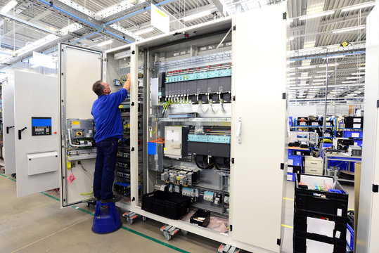 operator assembles machine in a factory - production of switch cabinets for industrial plant - Powered by Adobe