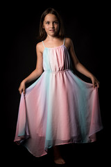 Obraz na płótnie Canvas Portrait of happy young little girl holding long colourful dress.
