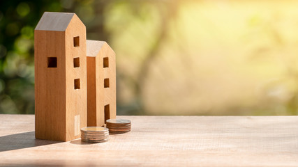 Wooden house or apartment model and  stack of coins with blur  background, loan or saving money for buy a house and real estate business investment concept.