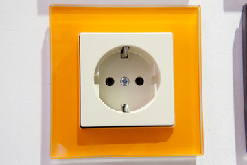 Modern European standard electrical outlet on the wall close up with orange border