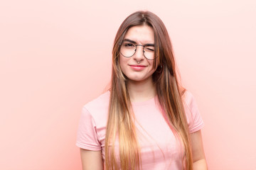 young pretty woman looking happy and friendly, smiling and winking an eye at you with a positive...