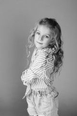 Fototapeta premium Black and white photo. Close up portrait of cheerful adorable teen girl posing in studio on isolated background. Teenage stylish model girl with curly hairstyle