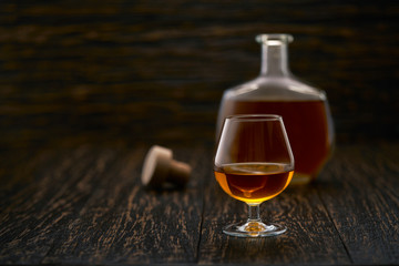 glass of cognac on a black wooden background.