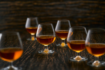 six glasses of  congac on a black background, selective focus.
