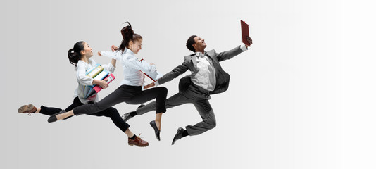 Happy office workers jumping and dancing in casual clothes or suit with folders on white. Ballet dancers. Business, start-up, working open-space, motion and action concept. Creative collage. Copyspace