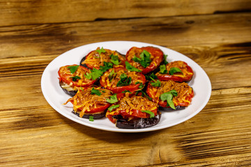 Baked eggplants with tomatoes and cheese on wooden table