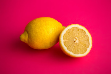  a lemon and a half cut lemon on a pink background