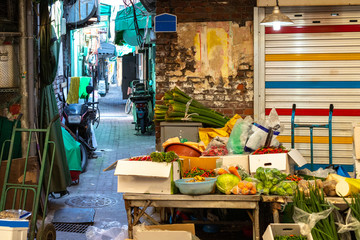 Narrow alley at the vegetable market. Colorful Asian street. Vegetables and greens on the market. Asian shopping street.
