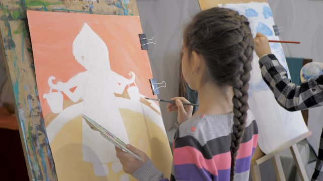 Girls paint pictures with paint on canvas. Lesson in art studio
