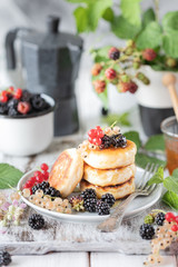 Homemade pancakes with berries, the blackberries, the honey on the plate, a branch of a BlackBerry alarm clock on white wooden background