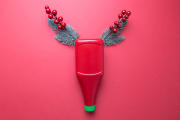 Ketchup bottle with horns made of christmas tree branches and red berries abstract on red.