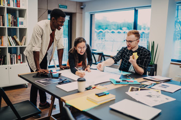 Fototapeta premium Young cheerful colleagues drawing plan