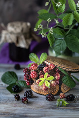 BlackBerry berry on a branch with leaves in a wooden carved box on a dark wooden background.