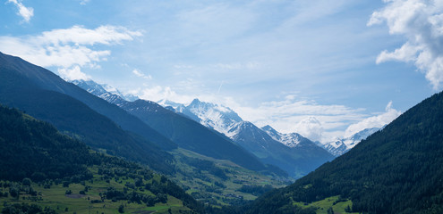Beautiful view of idyllic Swiss alpine mountains scenery with meadows and snow capped mountain peaks on a beautiful sunny day with blue sky in springtime. Beauty world.