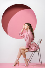 beautiful girl sitting on chair on white and pink