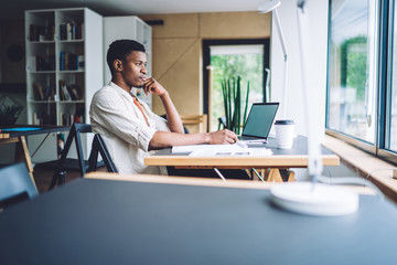 Pensive black man working at table in office