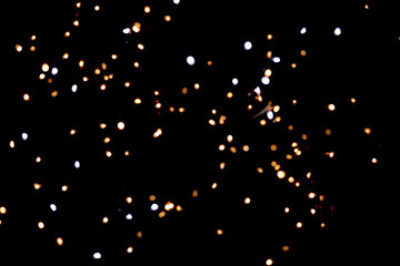 Golden glitter bokeh lights on black background, unfocused. Holiday time.