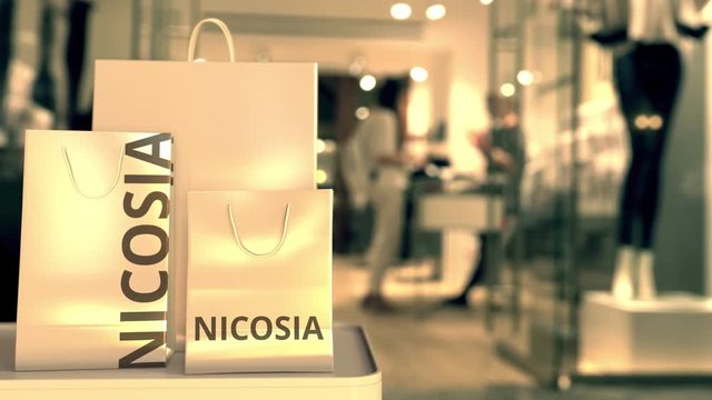 Paper shopping bags with Nicosia caption against blurred store entrance. Retail in Cyprus related conceptual 3D animation