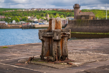An old wooden ship bollard on the West Pier with the Marina in the background, seen in Whitehaven, Cumbria, England, UK