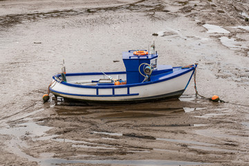 Naklejka premium A fishing boat in the mud of the Eller Beck in the harbour of Harrington, Cumbria, England, UK