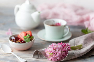 Spring Breakfast with granola and fresh strawberries and lychee and flowers on wooden background.