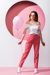 attractive woman holding balloon on pink and white