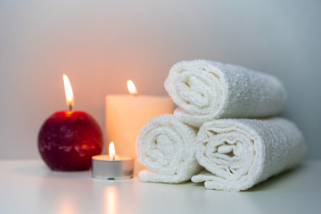 Natural health in SPA concept photo. White towels and candle lights.