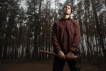 Strong lumberjack with the ax in the forest.Stylish lumberman getting ready for work. Lifestyle.