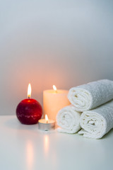 Obraz na płótnie Canvas Massage&SPA concept photo with candle lights and stack of white towels, vertical orientation.