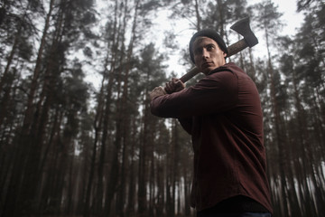  Lumberjack with the ax in the forest.Stylish lumberman getting ready for work. Hard iwork in the forest. Lumberjack chopping a tree. Lifestyle. 