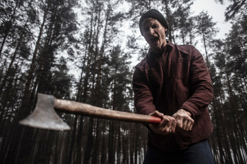  Lumberjack with the ax in the forest.Stylish lumberman getting ready for work. Hard iwork in the forest. Lumberjack chopping a tree. Lifestyle. 
