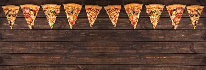 Tuinposter slices of tasty pepperoni pizza looking like christmas flags, creative holiday banner and concept of fast food on wooden background with copy space, top view © Alexander
