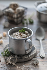 Hot mushroom cream soup of champignons with steam in a metal mug