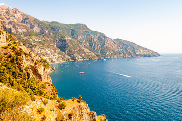 Obraz premium Beautiful scenic landscape of Positano. Rocky coastline full of boats and yachts traveling near high mountains. Cityscape of Positano surrounded by hills and deep blue Tyrrhenian sea waters